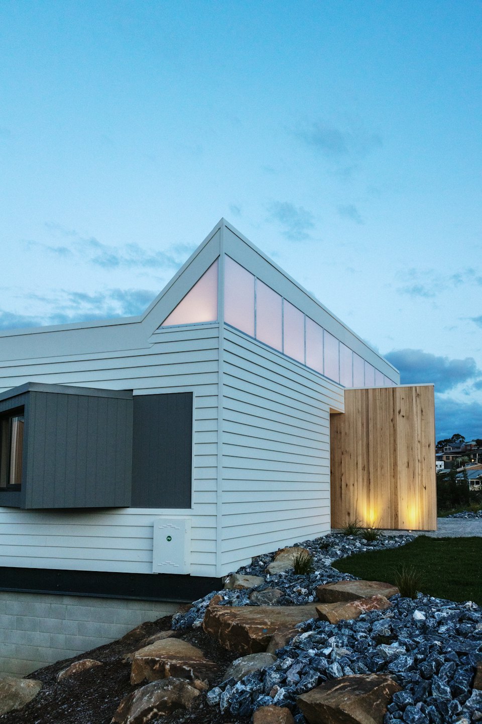 Modern house with wood paneling and rocky garden landscaping.